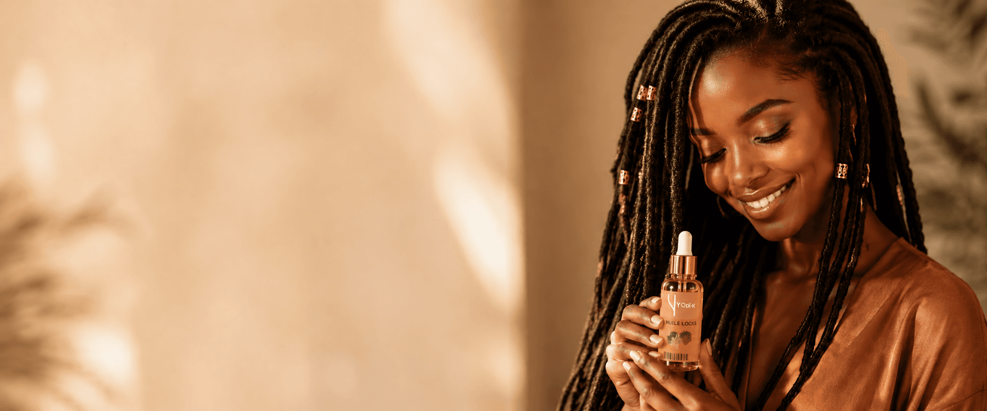 Femme africaine souriante avec de belles locs tenant l'huile Yodi-K